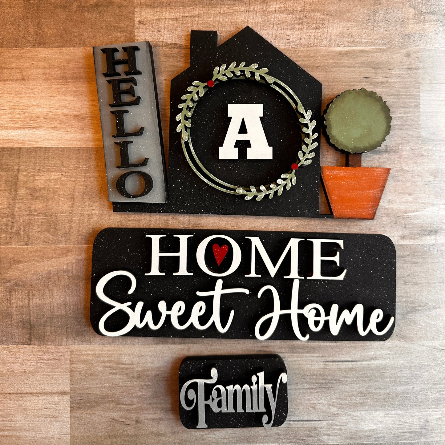 This is our Home Sweet Home insert that goes with our Vintage Truck. It shows a sign that reads “Hello,” a house with your choice of monogrammed letter, and a topiary that slides into the back of the truck's rails. The tailgate reads “Home Sweet Home,” and the license plate reads “Family.” These items include Velcro dots, allowing them to adhere to the Velcro on the truck base. All these items are hand-painted with love.