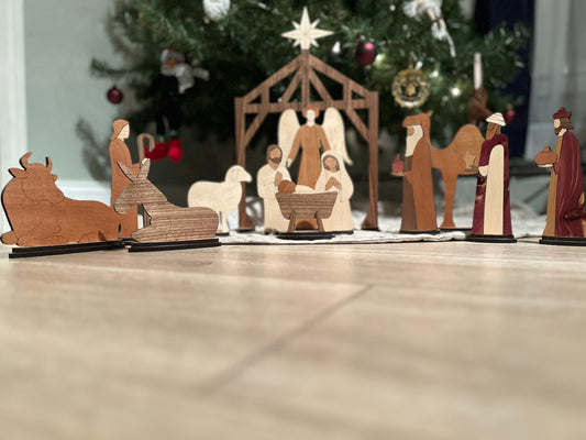 15 piece Wooden nativity scene with figures and stable in front of a Christmas tree.
