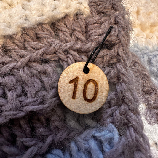 Wooden stitch marker with the number 10 on a knitted fabric. 
