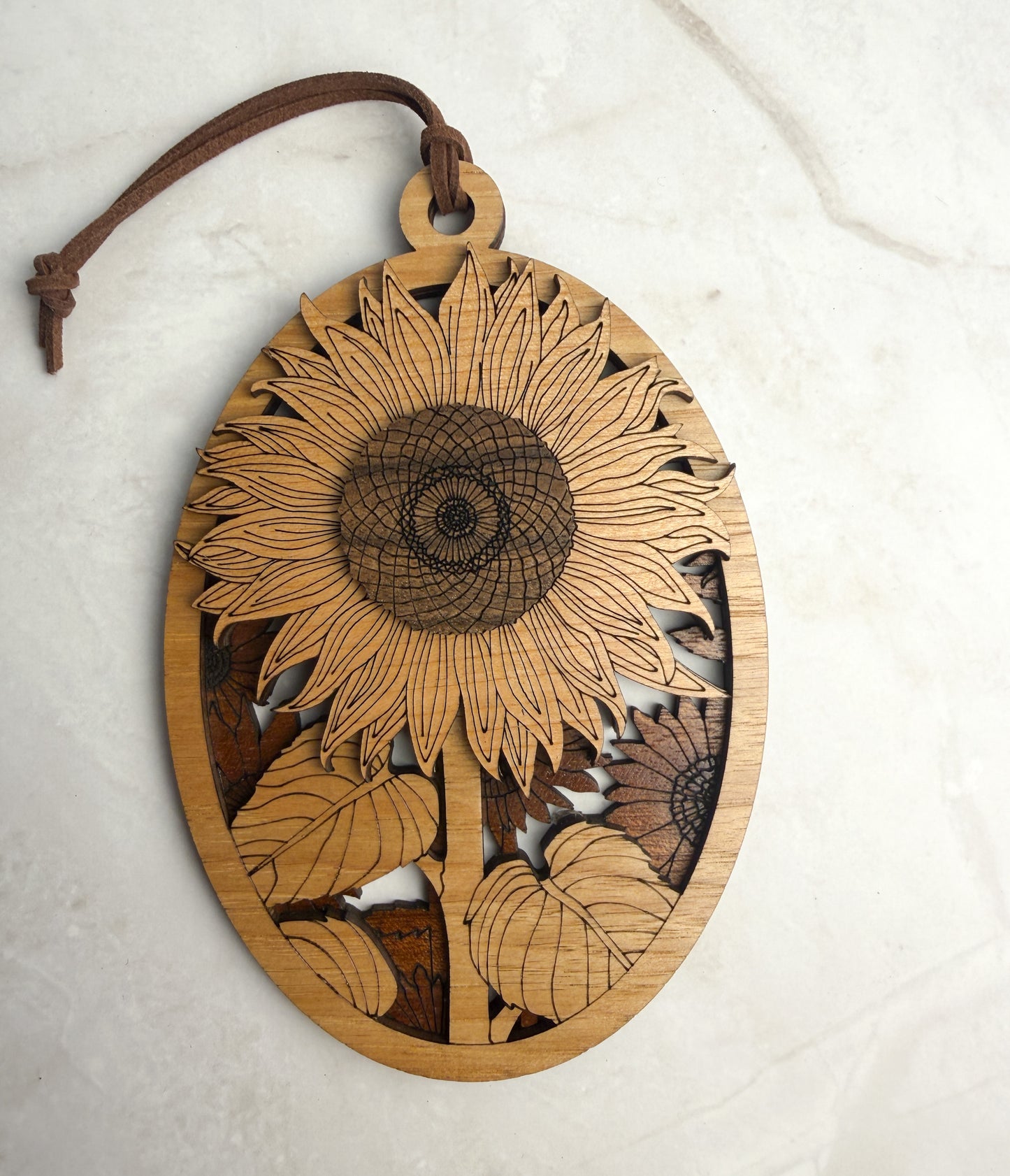 Wooden sunflower ornament with a leather strap on a white background