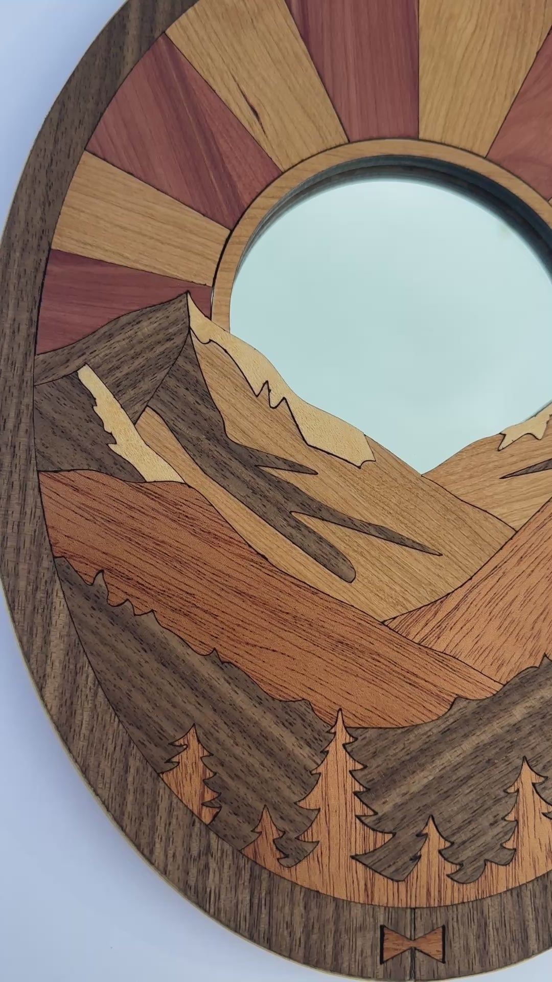 Video of a wood art piece with mountains and the sun.